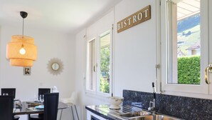 Una cocina moderna con un letrero que dice "BISTROT", un lavamanos y una zona de comedor con sillas y una mesa.