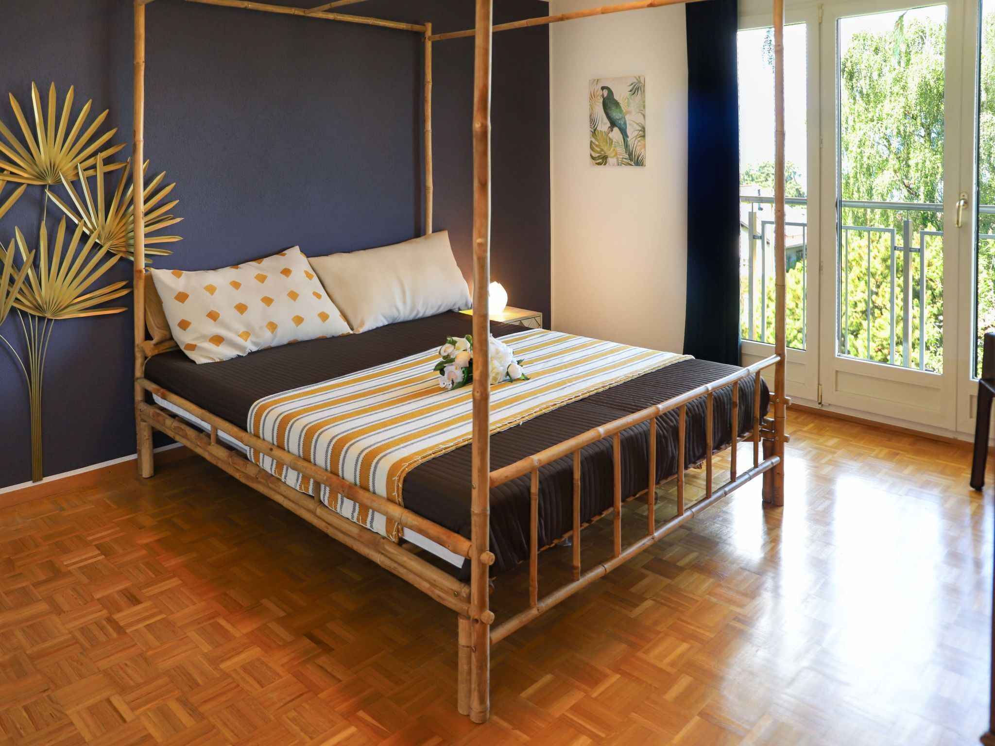 A four-poster bed with a dark brown frame, a striped bedspread, and two pillows with a geometric pattern.