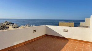 Une terrasse sur le toit offrant une vue sur la mer, avec un sol carrelé et un petit espace clos doté d’une fenêtre.
