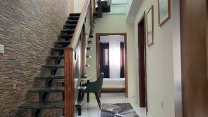 Un intérieur moderne avec un escalier, un banc et une vue sur une pièce à travers une porte vitrée.