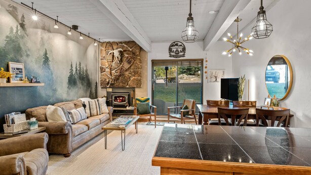 A cozy living room with a fireplace, a dining area, and a kitchen with a large island.