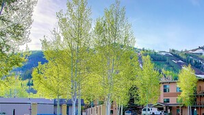 A hotel with a parking area, a building with a flat roof, and a mountain in the background.