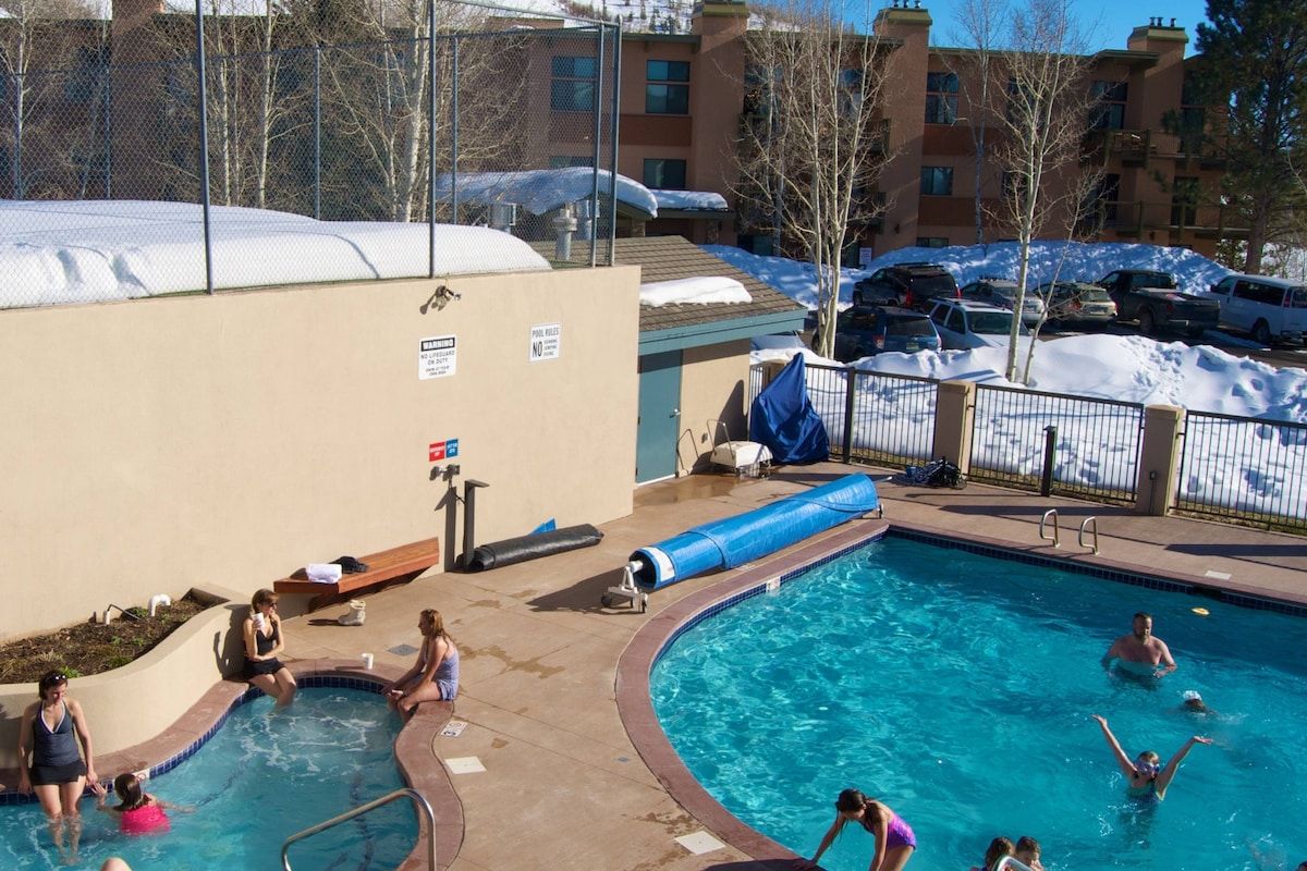 Una piscina con uno scivolo, circondata da una recinzione, e un edificio sullo sfondo.