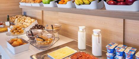 Un bufé con diversos alimentos, incluyendo frutas, pasteles y productos lácteos.