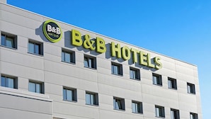 Un bâtiment d’hôtel-boutique avec une façade moderne, de nombreuses fenêtres et un ciel dégagé.