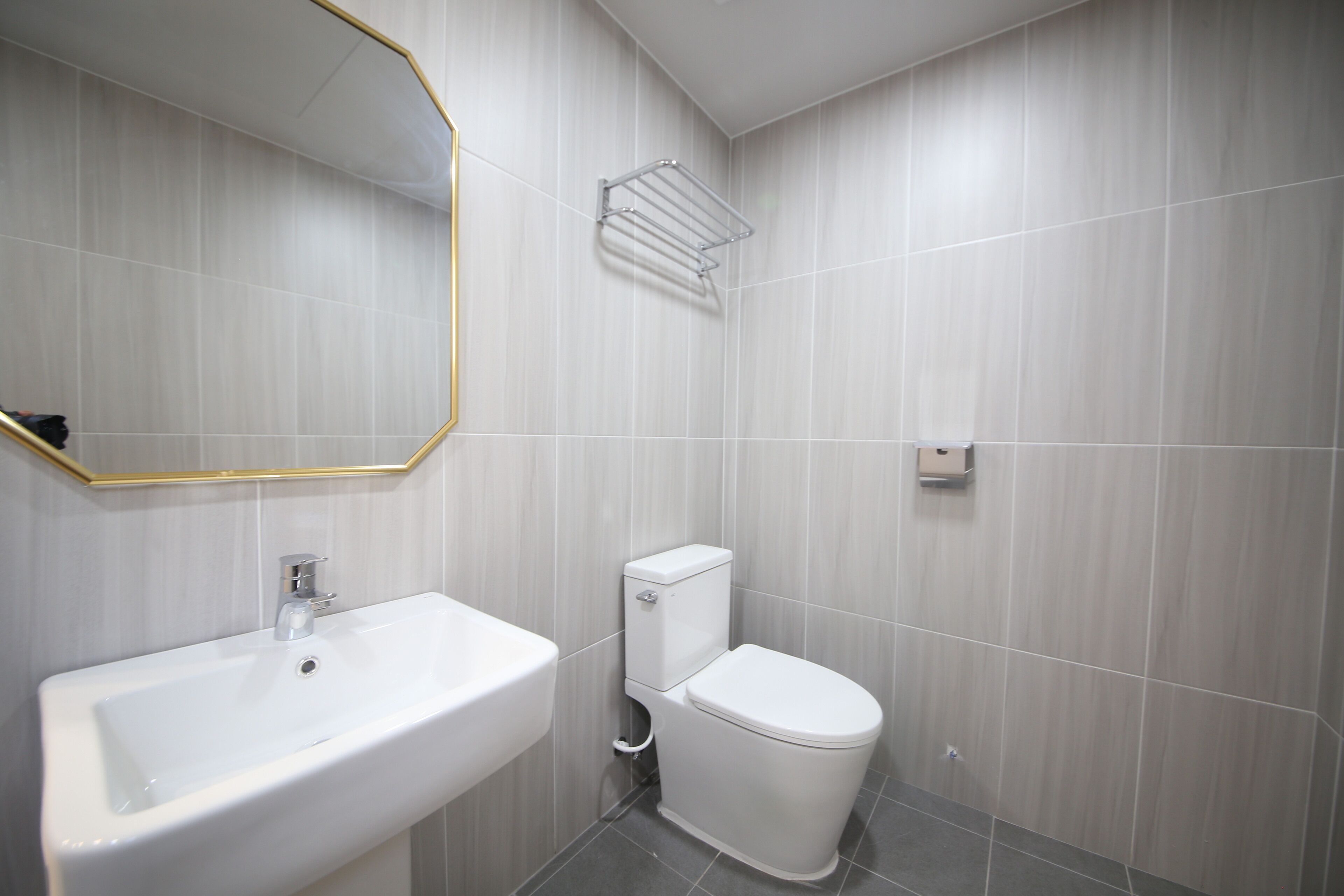 Un baño con lavamanos blanco, inodoro y un perchero para toallas.