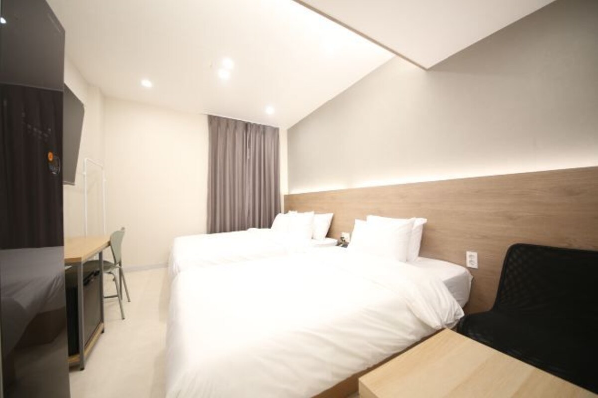 A modern hotel room with a large bed, a desk, and a chair.