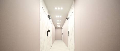 A corridor with lockers and a tiled floor, leading to a door at the end.