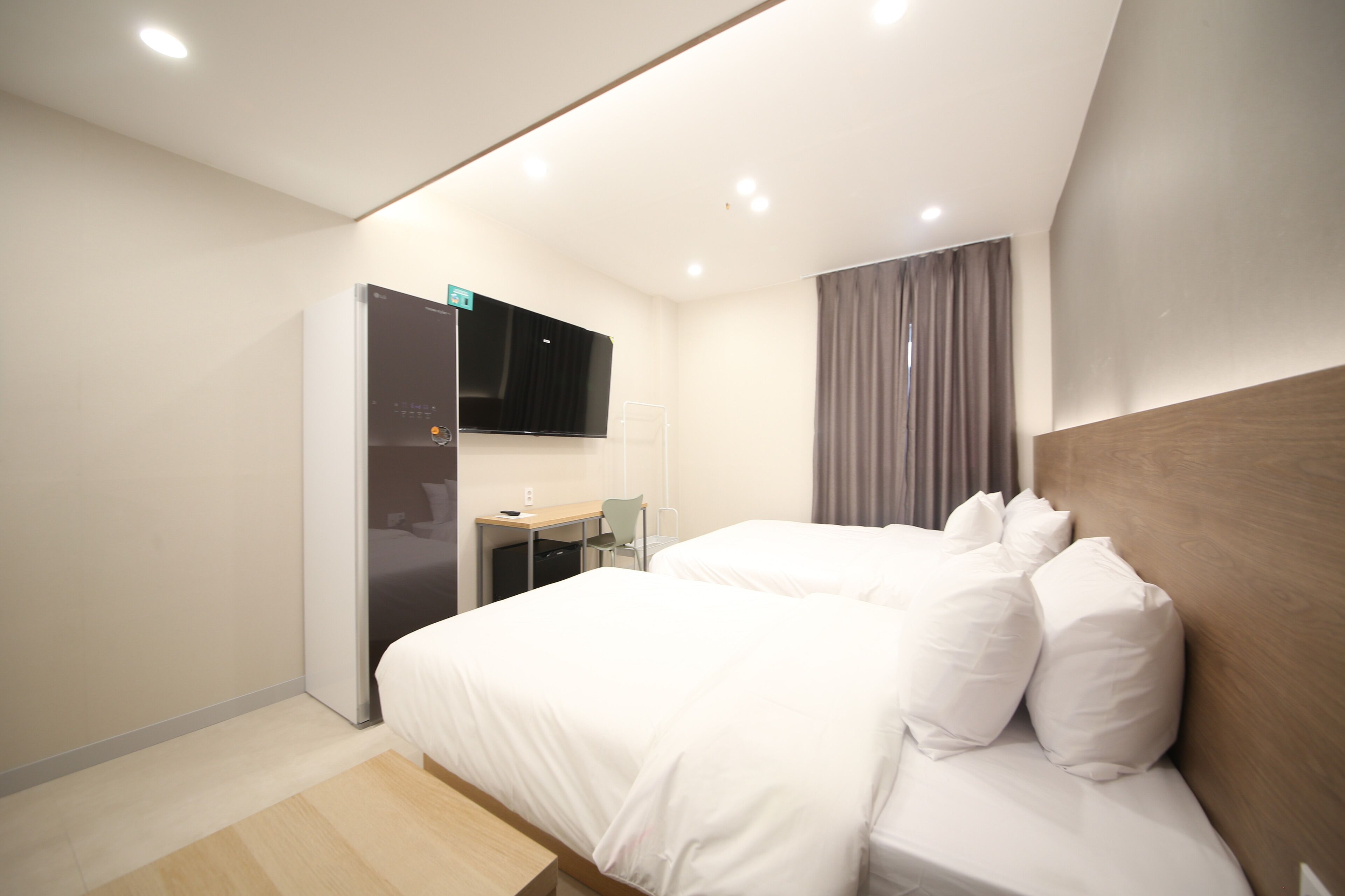Une chambre d’hôtel moderne, dotée d’un grand lit, d’un bureau et d’un téléviseur à écran plat fixé au mur.