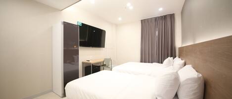 Une chambre d’hôtel moderne, dotée d’un grand lit, d’un bureau et d’un téléviseur à écran plat fixé au mur.