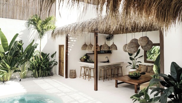 Un intérieur de style tropical, avec un toit de chaume, une piscine et une végétation luxuriante.