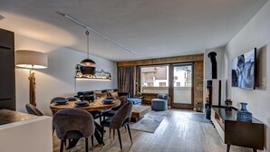 Een moderne woonkamer met een eethoek, houten vloeren en een open haard.