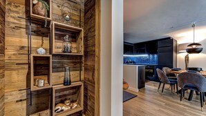 Een moderne keuken met een ingebouwd eiland, donkere kastjes en een eethoek met gestreept stoelen.