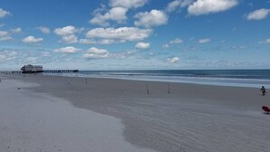 Une plage avec une jetée et un bâtiment en arrière-plan.