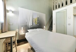 A hotel room with a bed, a desk, a chair, a window with curtains, and a staircase. - B&B Hotel Le Mans Sud (Arnage)