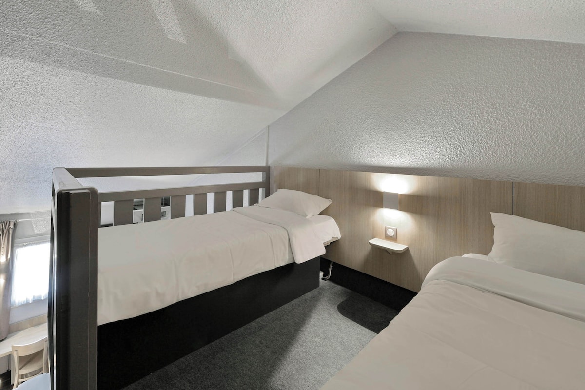 Een hotelkamer met twee bedden, een bureau en een nachtkastje met een lamp.