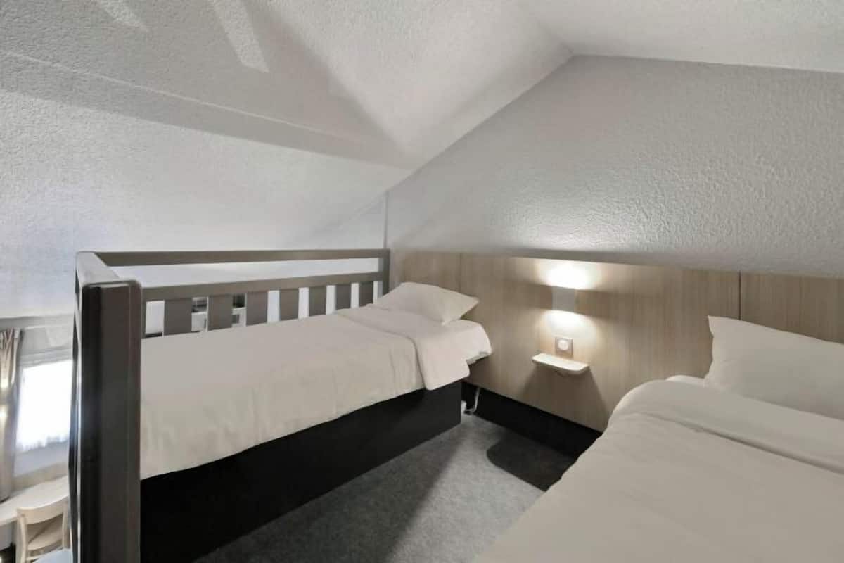 Een slaapkamer met twee bedden, een nachtkastje en een wandlamp.