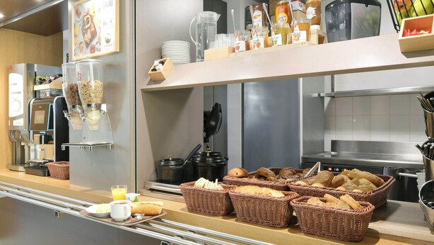 A breakfast buffet with various food items, baskets of bread, and kitchen appliances.