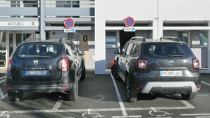 Two Duster cars parked in a parking lot with a building labeled 'ACCUEIL' in the background.