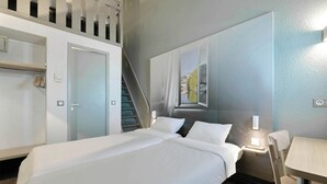 A hotel room with a bed, a desk, a chair, a staircase, and a large window with a view.
