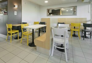 L’intérieur d’un restaurant, avec des tables et des chaises, un comptoir et un miroir au mur.