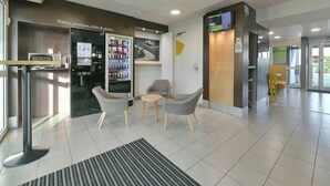 A modern lobby with seating, a vending machine, and a digital display.
