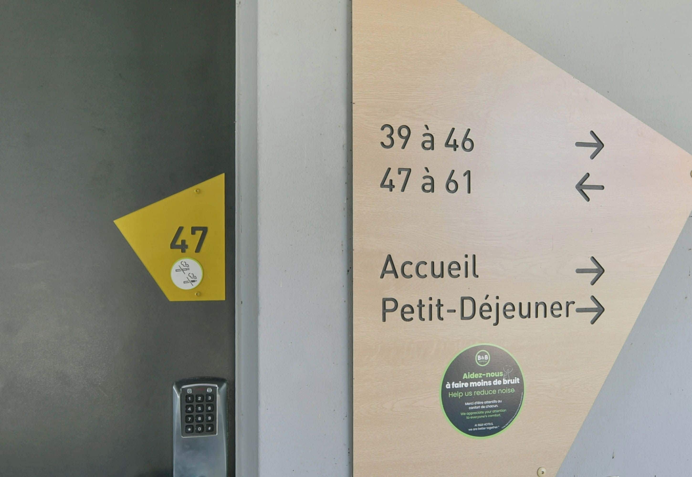 A directional sign with arrows pointing to different room numbers and a label for 'Accueil Petit-Déjeuner'.