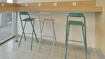 Three foldable chairs, a wooden shelf with electrical outlets, and a tiled floor.