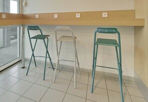 Tres sillas plegables, un estante de madera con enchufes y un suelo de baldosas.