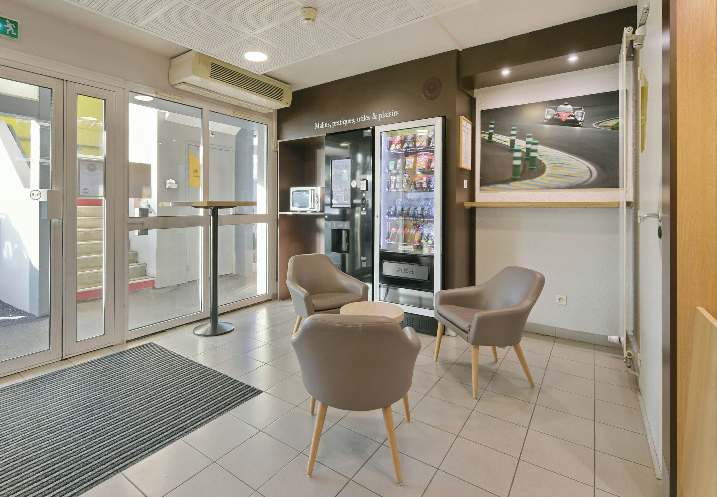 A reception area with a seating arrangement, a vending machine, and a wall-mounted artwork.