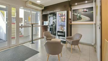 A reception area with a seating arrangement, a vending machine, and a wall-mounted artwork.