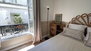 Une chambre à coucher avec un lit, une table de chevet, une lampe et une fenêtre avec des rideaux.