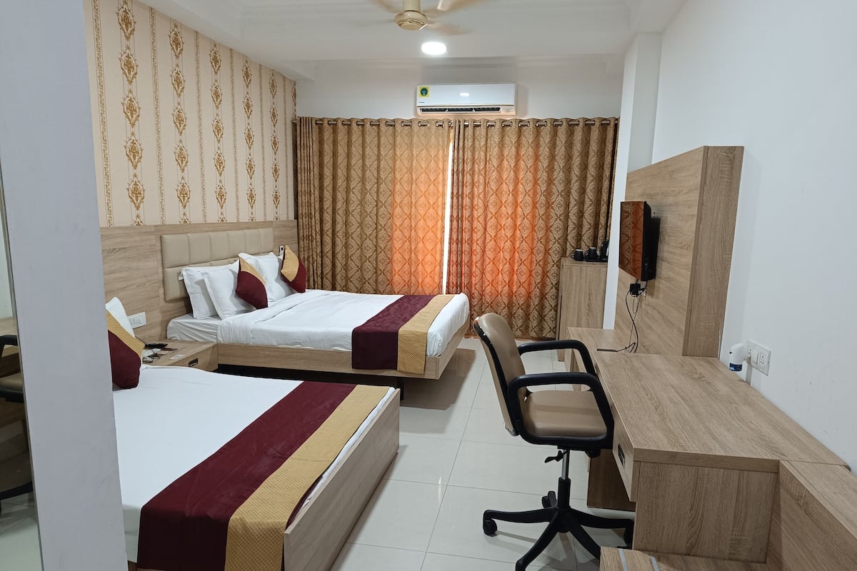 Une chambre d’hôtel avec deux lits, un bureau, une chaise, un appareil de climatisation et un téléviseur.