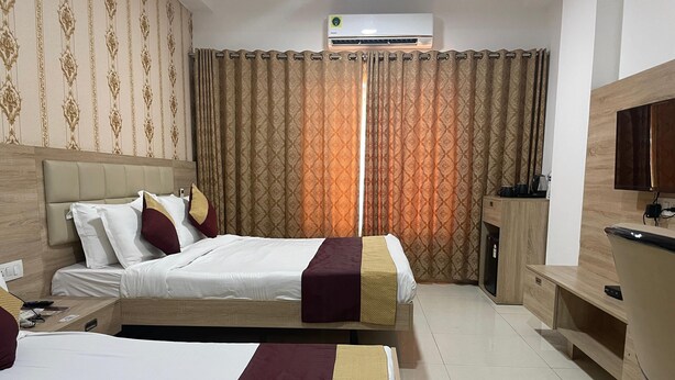 Une chambre d’hôtel avec deux lits, une télévision, une armoire et un appareil de climatisation.