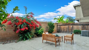 A patio area with a brick wall, a wooden fence, and a concrete floor.