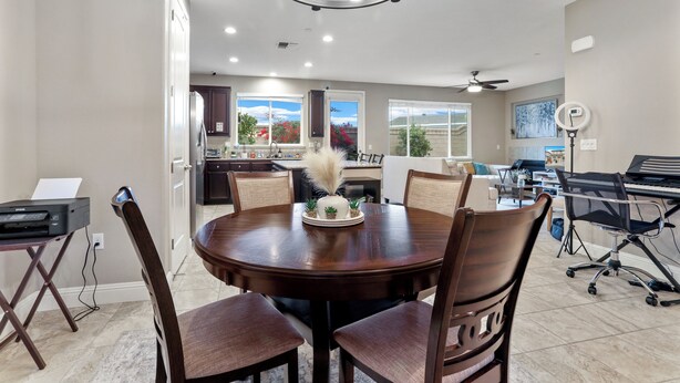 A dining area with a round table, four chairs, and a chandelier.