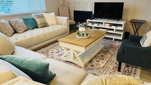 A living room with a beige sofa, a wooden coffee table, and a TV stand with a flat-screen TV.