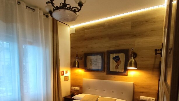 A neatly made bed with a headboard, bedside lamps, and a chandelier. - STUDIOS OR PRIVATE ROOMS (Barcelona)