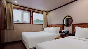 Camera d'albergo con due letti, una testiera in legno, un comodino, uno specchio e una finestra con tende.