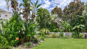 A well-maintained garden with a variety of tropical plants and a neatly trimmed lawn.