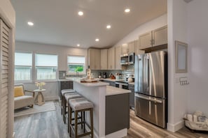 Una cocina moderna con una isla central, electrodomésticos de acero inoxidable y vistas al exterior.