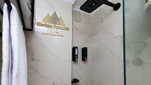 Une salle de bain avec des carreaux de marbre blanc, une pomme de douche et un porte-serviettes.