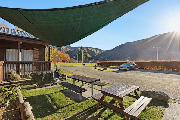 Un espacio al aire libre cubierto con mesas de picnic, una parrilla para barbacoa y vistas a una cordillera.