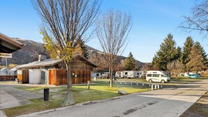 A campground with a wooden cabin, a kitchen area, and RVs parked. - Hampshire Holiday Parks - Arrowtown (Arrowtown)