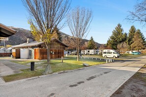 Un terrain de camping avec une cabane en bois, un espace cuisine et des camping-cars stationnés.