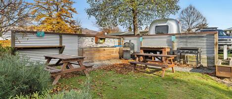 A backyard with a grill, picnic table, and a small shed.
