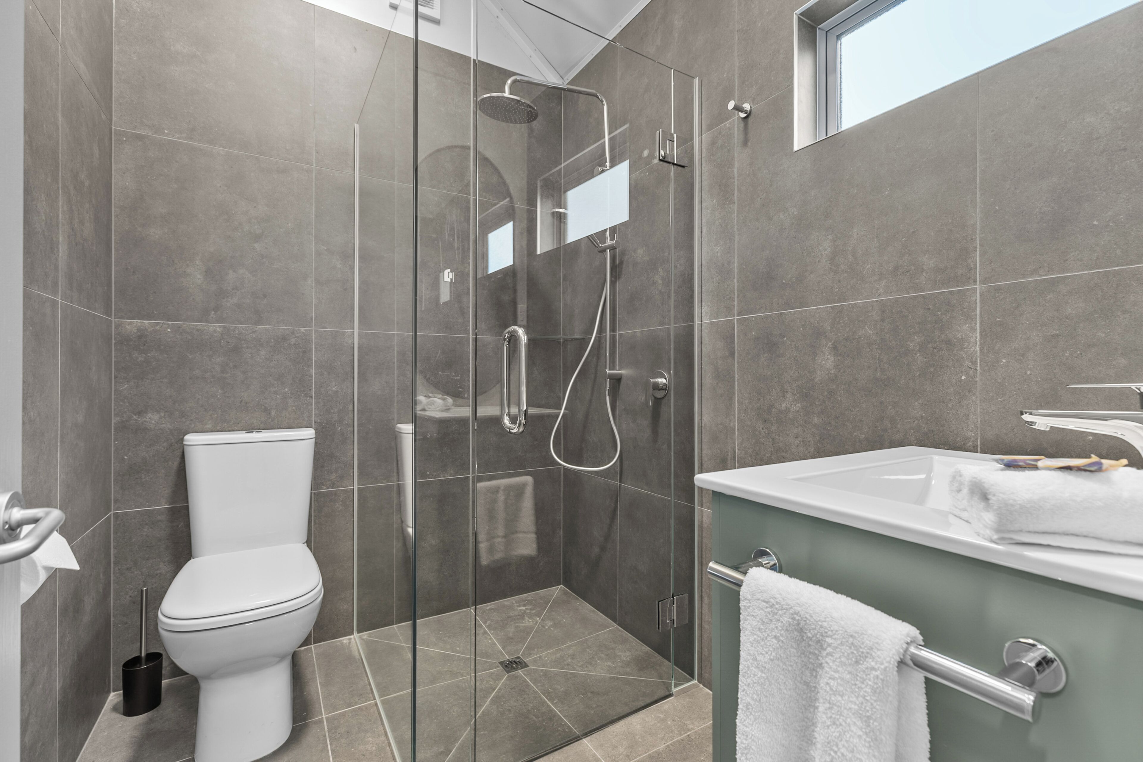 Een moderne badkamer met een douchecabine, een toilet en een wastafel met een handdoek.