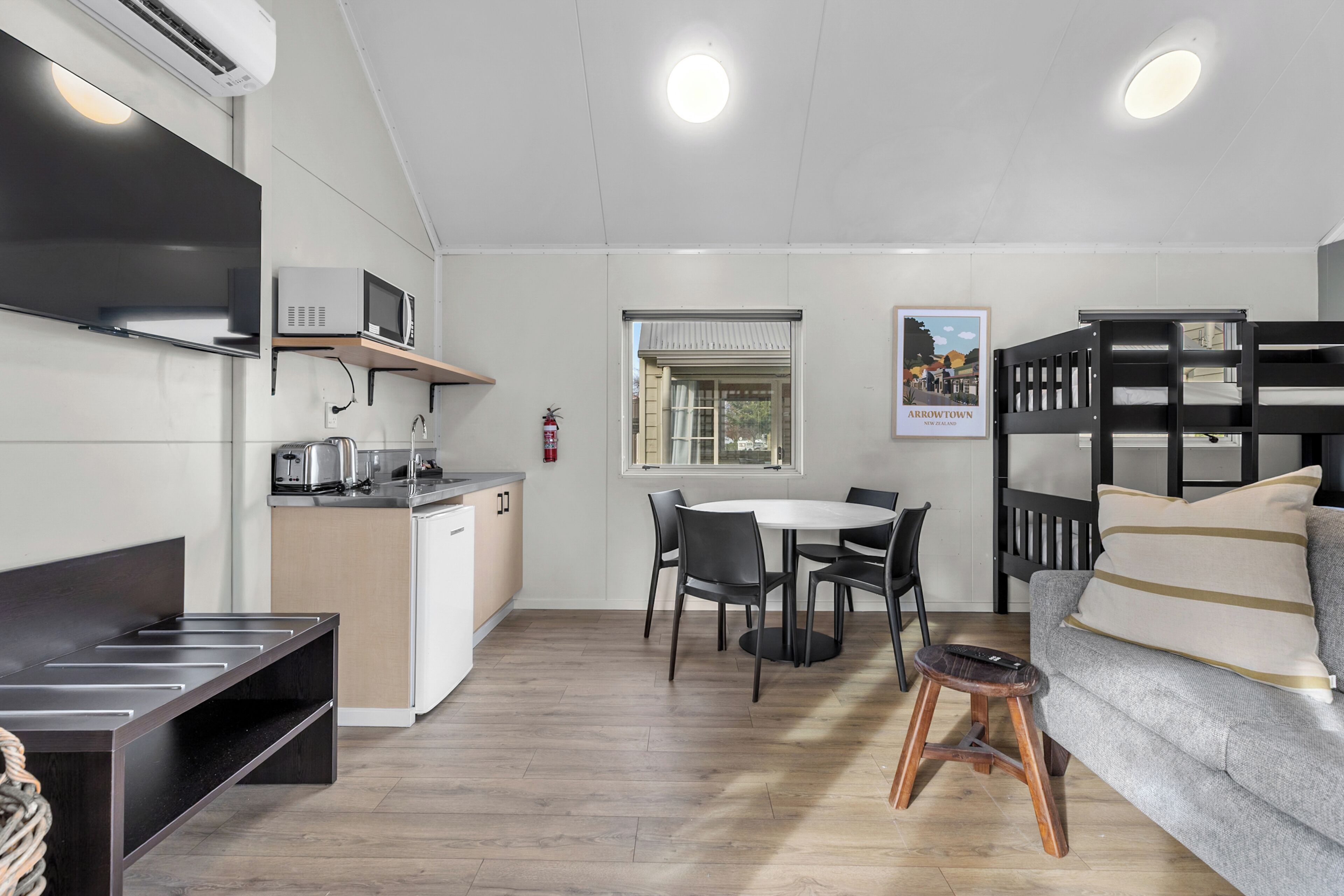 A compact living space with a kitchenette, dining area, and a bunk bed.