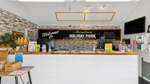 A reception desk with a brick wall backdrop, a welcome sign, and a sign for Arrountown Holiday Park. - Hampshire Holiday Parks - Arrowtown (Arrowtown)