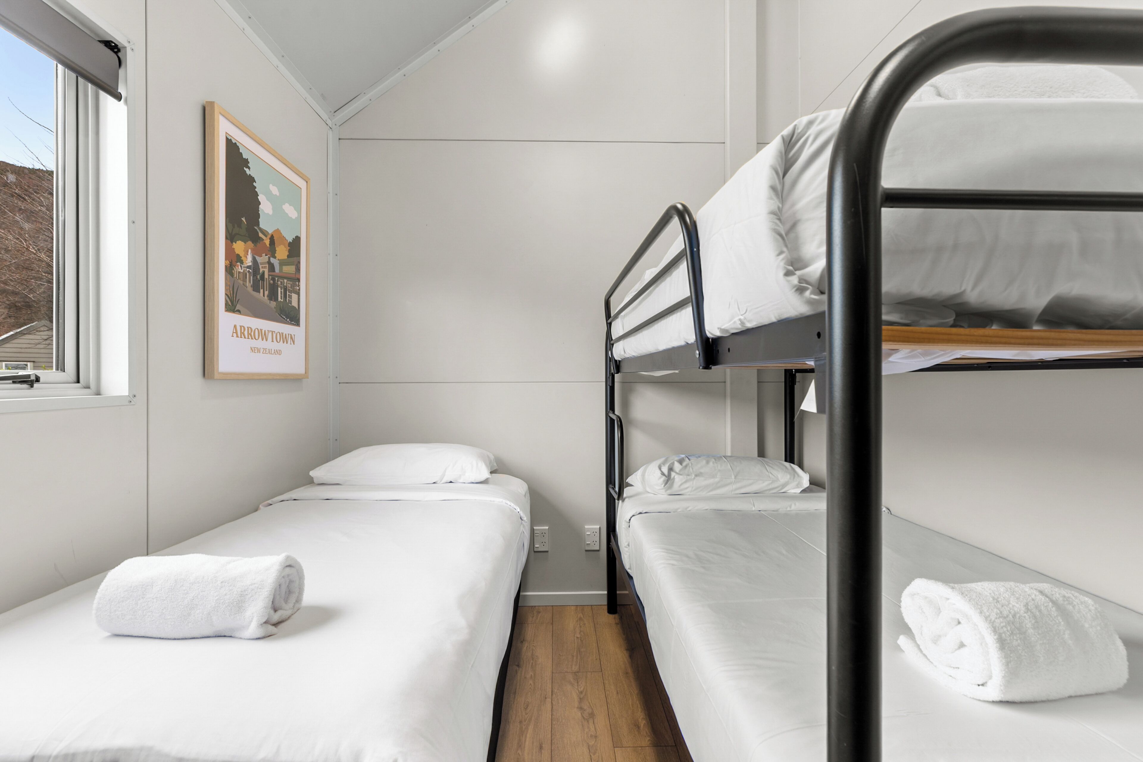 A bunk bed room with white bedding and a framed picture on the wall.